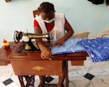A girl using a sewing machine in a taloring workshop